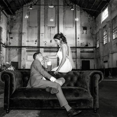 Fotograaf in Assendelft | Zwart wit Trouwfoto van stel op een bank in een oude hal op het Hembrug terrein in Zaandam.