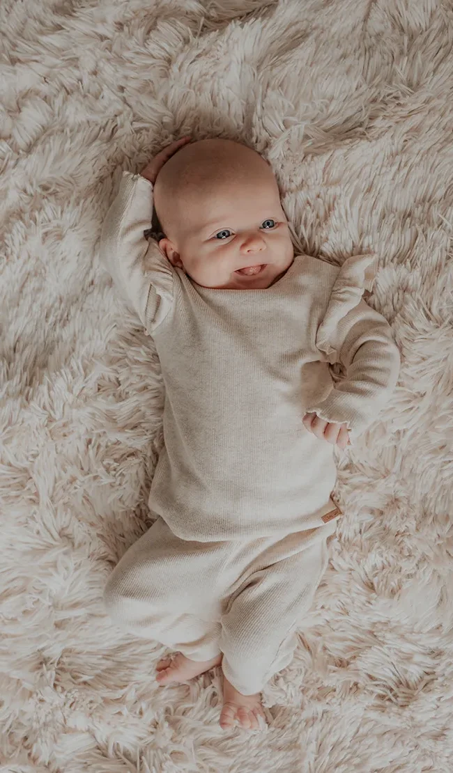 Newbornshoot noord holland lachende baby op flokati