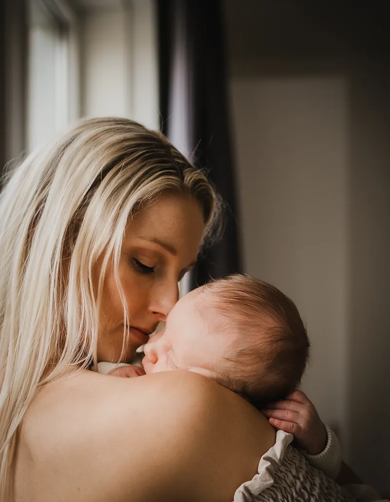 Mama met baby tijdens newbornshoot thuis in noord holland